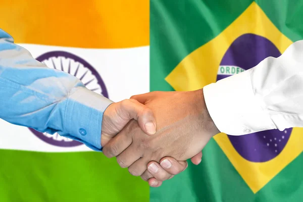 handshake on Brazil and India flag background.