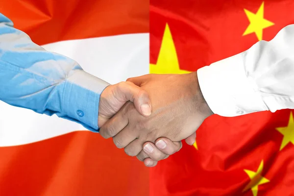 handshake on Austria and China flag background.