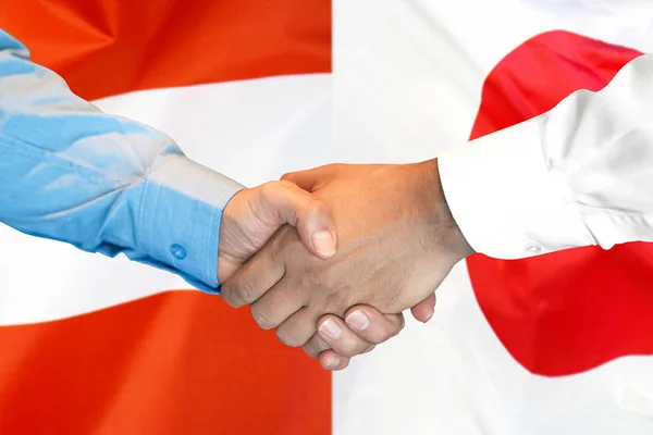 handshake on Austria and Japan flag background.