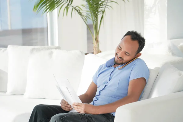 Happy entrepreneur man reading good news in a letter on sofa in home.