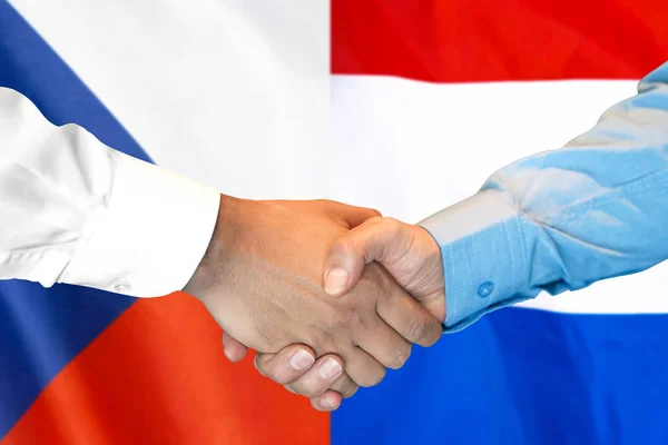Podání ruky na pozadí vlajky České republiky a Nizozemska. — Stock fotografie