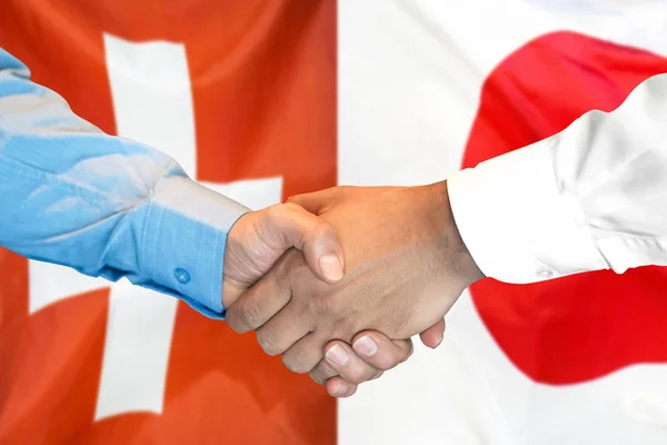 Handshake op Zwitserland en Japan vlag achtergrond. — Stockfoto