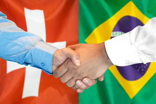 Handshake op Zwitserland en Brazilië vlag achtergrond. — Stockfoto