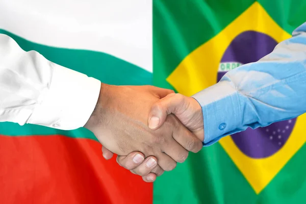 Aperto de mão no fundo da bandeira da Bulgária e do Brasil . — Fotografia de Stock