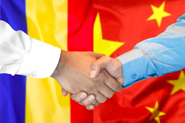 handshake on Moldova and China flag background.