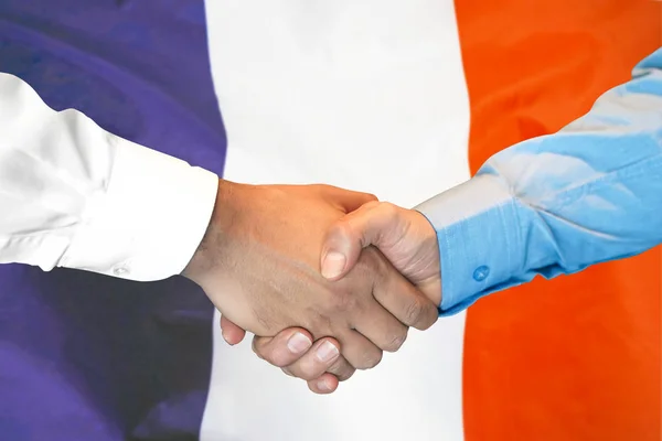 Handskakning på Frankrike flagga bakgrund. — Stockfoto