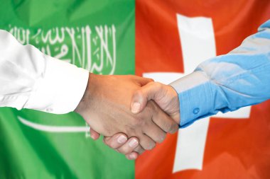 Suudi Arabistan ve İsviçre bayrağı arka planda el sıkışma.