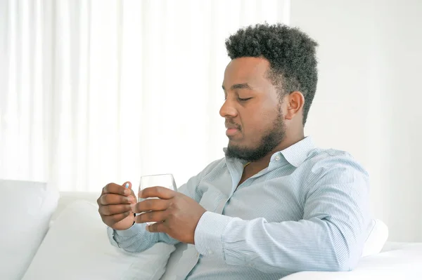 African man drinks a pill from pain