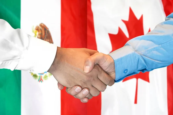 Podání ruky na pozadí vlajky Mexika a Kanady. — Stock fotografie