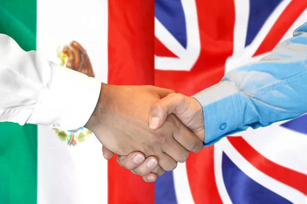 Apretón de manos en el fondo de la bandera de México y Reino Unido . — Foto de Stock