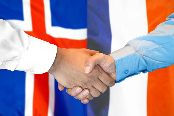 Kézfogás Izland és Franciaország lobogó szerinti hátterére. — Stock Fotó