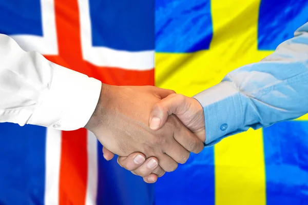 Kézfogás Izland és Svédország zászlói hátterére. — Stock Fotó