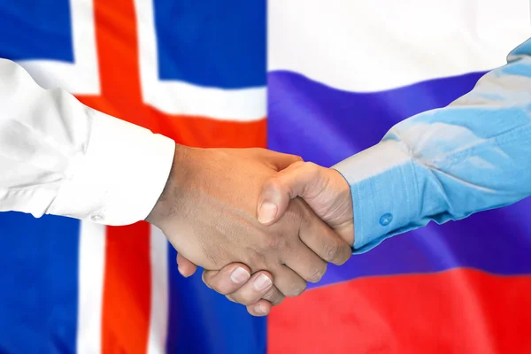 handshake on Iceland and Russia flag background.