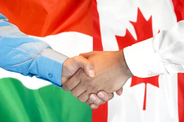 Apretón de manos en el fondo de la bandera de Hungría y Canadá . — Foto de Stock