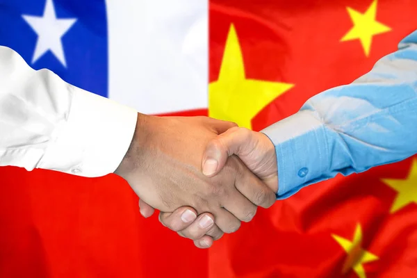 handshake on Chile and China flag background.