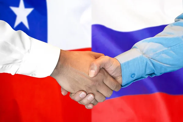 Podání ruky na pozadí vlajky Chile a Ruska. — Stock fotografie