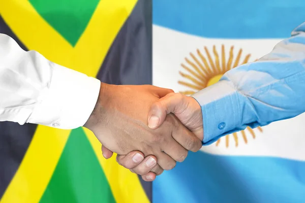 Apretón de manos sobre fondo de la bandera de Jamaica y Argentina . —  Fotos de Stock