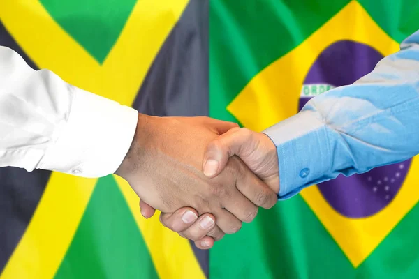 Aperto de mão no fundo da bandeira da Jamaica e Brasil . — Fotografia de Stock