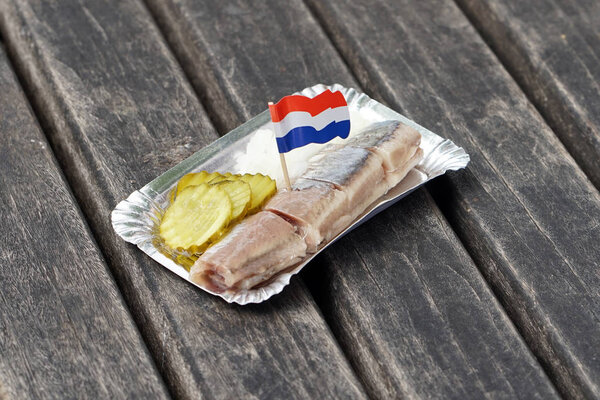 Dutch snack, seafood sandwich with herring, onions and pickled cucumber.