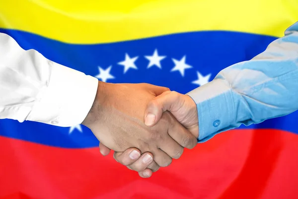 Handshake on Venezuela flag background.