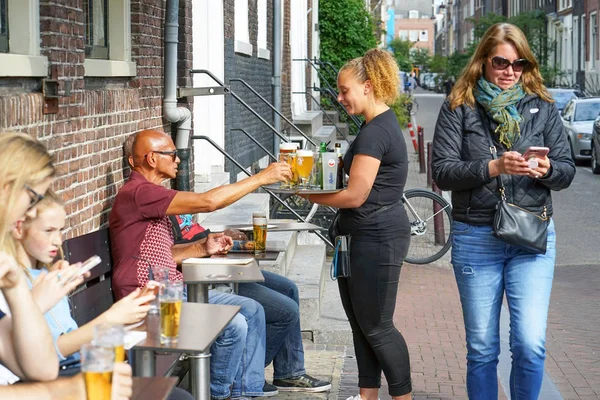 Waitress serving a client in restaurant, cafe, bar. The concept of service. Street cafe in Amsterdam. — Stock Photo, Image