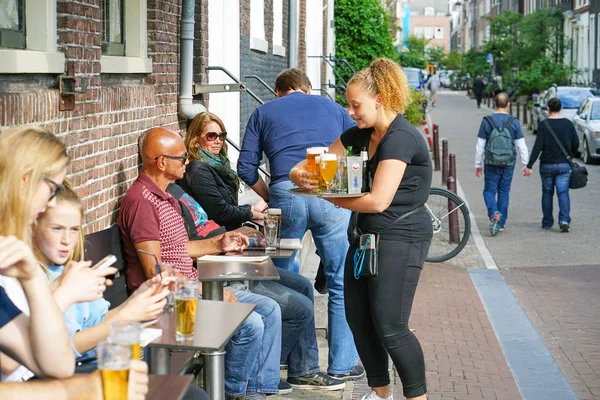 Waitress serving a client in restaurant, cafe, bar. The concept of service. Street cafe in Amsterdam. — Stock Photo, Image