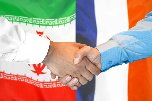 Aperto de mão no fundo da bandeira do Irão e da França . — Fotografia de Stock