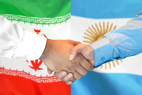 Mano apretada sobre fondo de la bandera de Irán y Argentina . — Foto de Stock