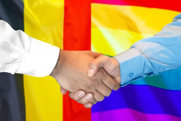 Handshake op België en LGBT Gay Flag achtergrond. — Stockfoto