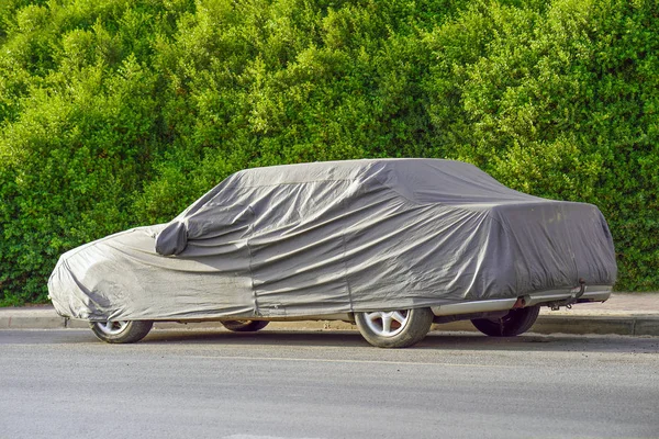 Um carro estacionado com tampa protetora em tempo de sol — Fotografia de Stock