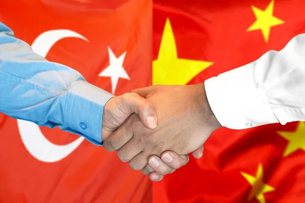 Handshake on Turkey and China flag background.