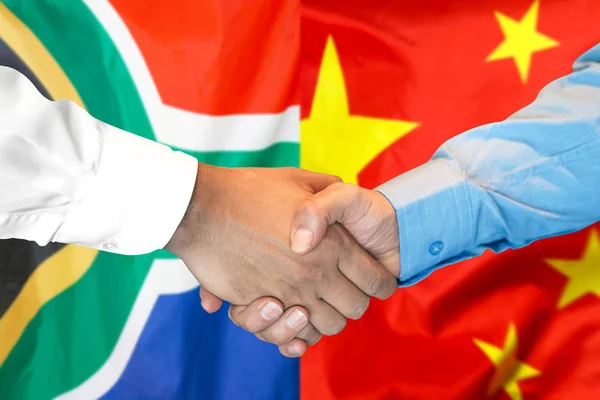 Handshake on South Africa and China flag background.