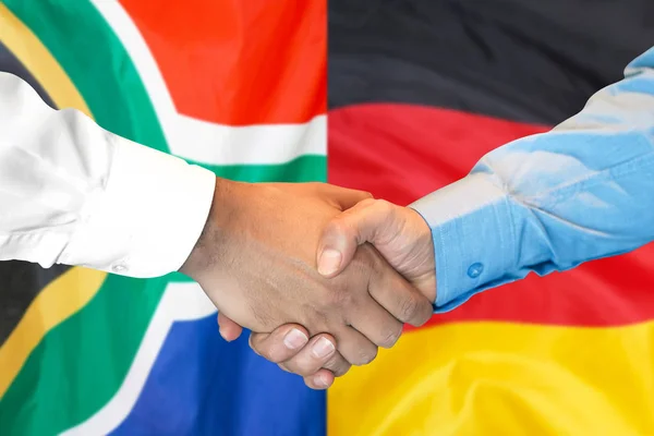 Handshake on South Africa and Germany flag background.