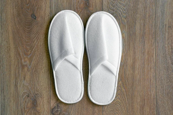Top view of a pair white slippers in the hotel on wooden floor.