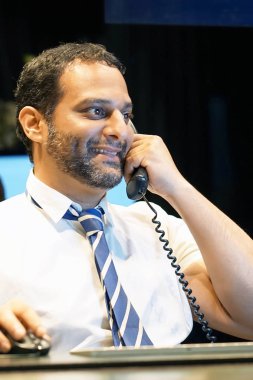 İş adamı iş yerinde telefonda konuşuyor. Telefona cevap veren ve müşteri hizmetleri merkezindeki bilgisayar monitörüne bakan bir erkek ofis çalışanının kapatılması.                               