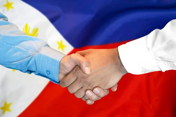 Handshake on Philippines flag background.