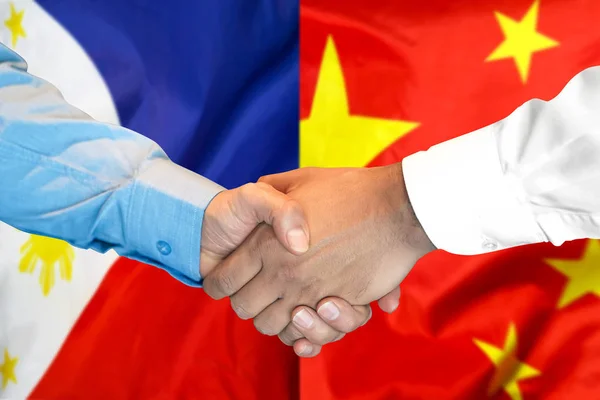 Handshake on Philippines and China flag background.