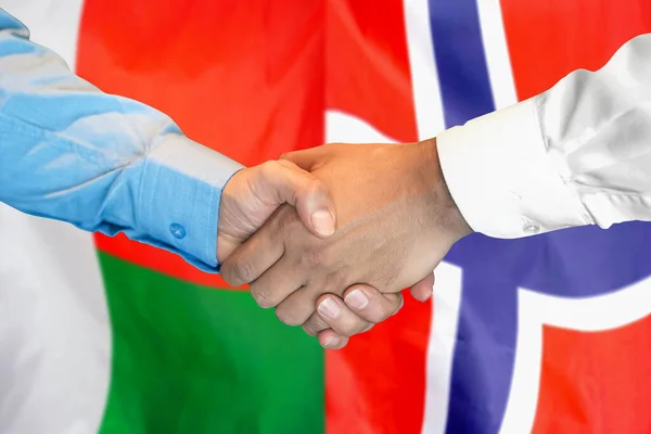 在两面旗帜的背景下进行商业握手 男人们在马达加斯加和挪威国旗的背景下握手 支助概念 — 图库照片