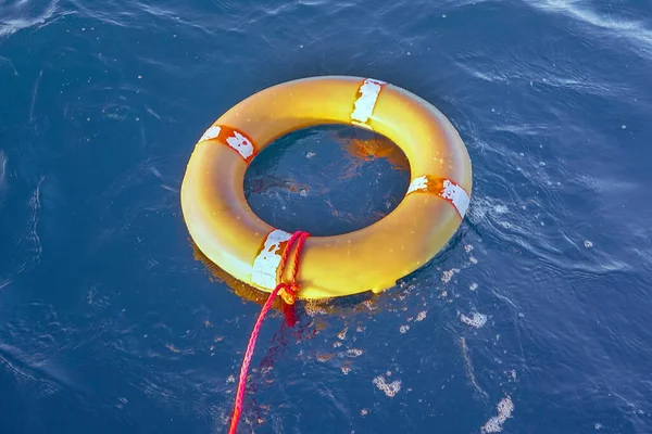 水の上に青い海のロープを持つ黄色の救命艇 生命リングは水の上に浮かんでいます 海にロープを持つ生命リング — ストック写真