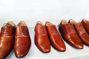 Klasik kahverengi deri erkek ayakkabıları bir mağazanın beyaz rafında. Moda klasik cilalı kahverengi erkek ayakkabıları rafta. Satış ve alışveriş konsepti. Seçici odak