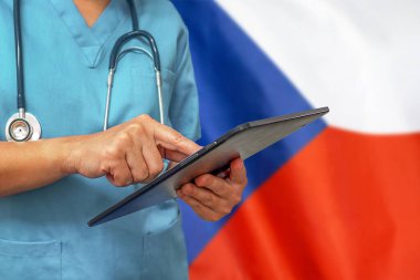 Cerrah ya da doktor, Çek Cumhuriyeti bayrağının arka planında dijital tablet kullanıyor. Çek Cumhuriyeti 'nde tıbbi teçhizat veya tıbbi ağ, teknoloji ve tanı.