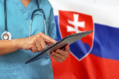 Doktor ya da doktor, Slovakya bayrağının arka planında dijital tablet kullanıyor. Slovakya 'da tıbbi ekipman veya tıbbi ağ, teknoloji ve tanı.