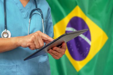Cerrah ya da doktor Brezilya bayrağının arka planında dijital tablet kullanıyor. Brezilya 'da tıbbi ekipman veya tıbbi ağ, teknoloji ve tanı.