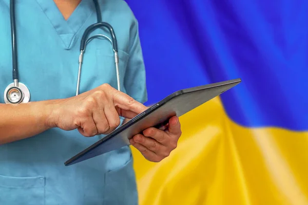 Cerrah ya da doktor Ukrayna bayrağının arka planında dijital tablet kullanıyor. Ukrayna 'da tıbbi ekipman veya tıbbi ağ, teknoloji ve tanı.