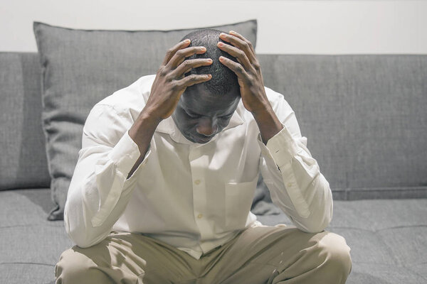 Грустное лицо депрессивного африканца старшего возраста. Очень грустный старик. Портрет грустного пожилого человека крупным планом. Одинокий африканский мужчина грустит, сидя дома на кровати. Человек чувствует депрессию.