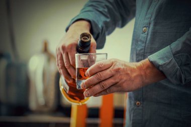 Mutfakta viski şişesi olan yaşlı beyaz bir adamın elleri. Sarhoşluk ve alkolizm kavramı. Alkolik baba. Tonlama