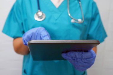 Eldivenli doktor ya da doktor dijital tablet kullanıyor. Eldivenli cerrah dijital tablete mesaj yazıyor.