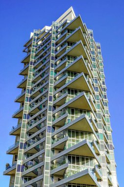 Mavi gökyüzüne karşı modern gökdelen ofis binaları. Yüksek bina. Modern şehir mimarisi. Camdan ve betondan yapılmış evler. Aşağıdan gökdelenlerin görüntüsü.