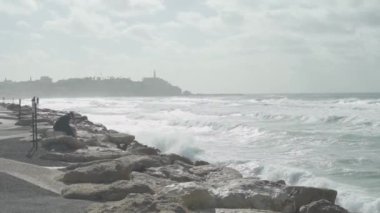 Yaşlı bir adam İsrail 'in eski Jaffa kentinin yanındaki kayalarda oturuyor.