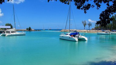 Katamaran ve mavi su ve taş iskele Seyşeller feelin bir cennet kartpostal üzerinde güzel bir koyda Yelkenli tekne ile bir yat limanı
